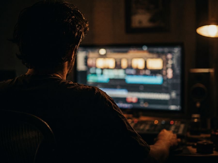 Editor cutting an episode in a dark edit suite