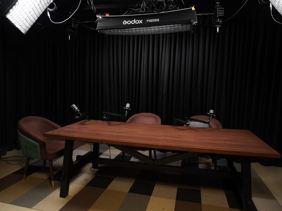 Podcast set lit and ready, three mics on the table